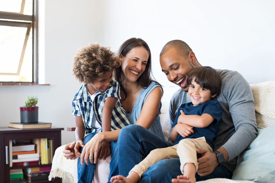 A smiling family sitting on a couch togther