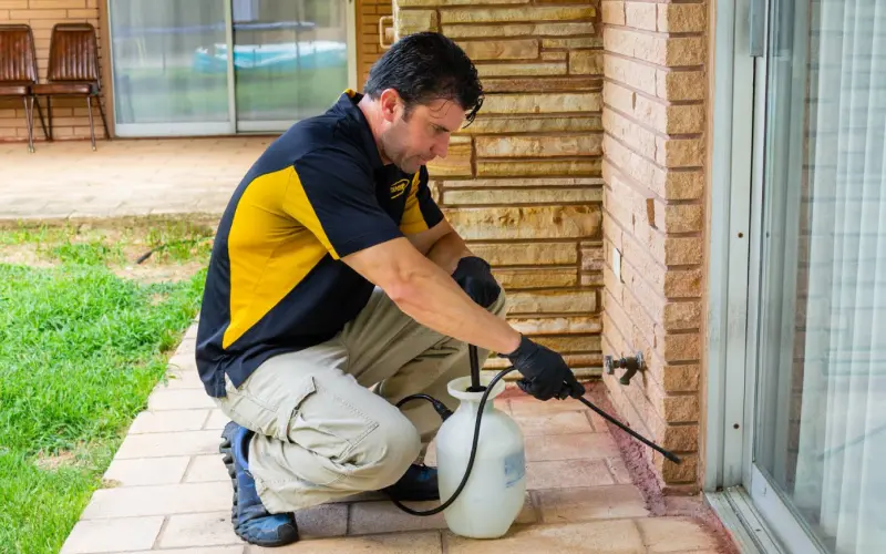 An Advanced Pest Control technician sprays the exterior of a home in Garland County, AR.